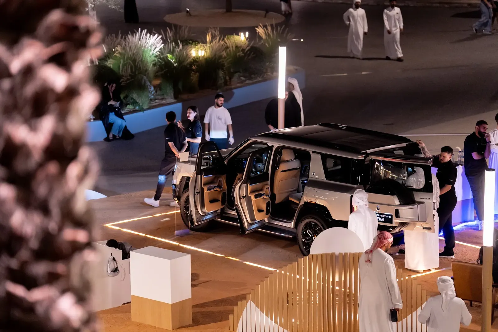 Overhead view of guests around an open-door Denza B8 on the sand podium