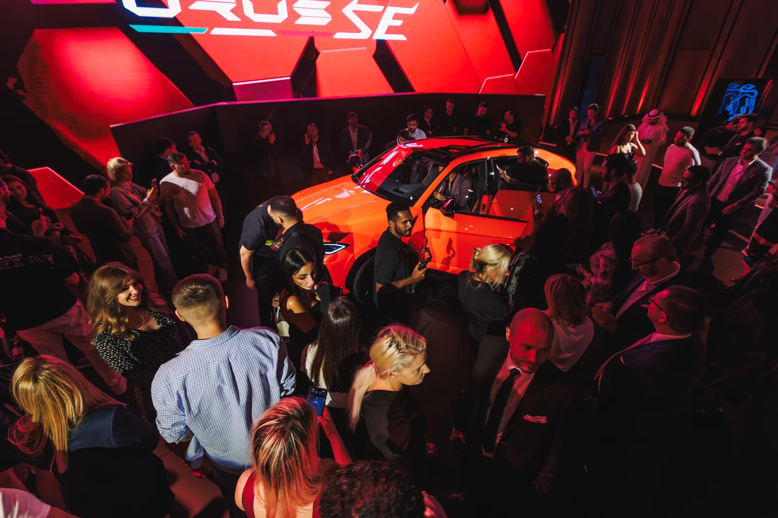 Guests gathered around the orange Urus SE beneath the Urus SE sign