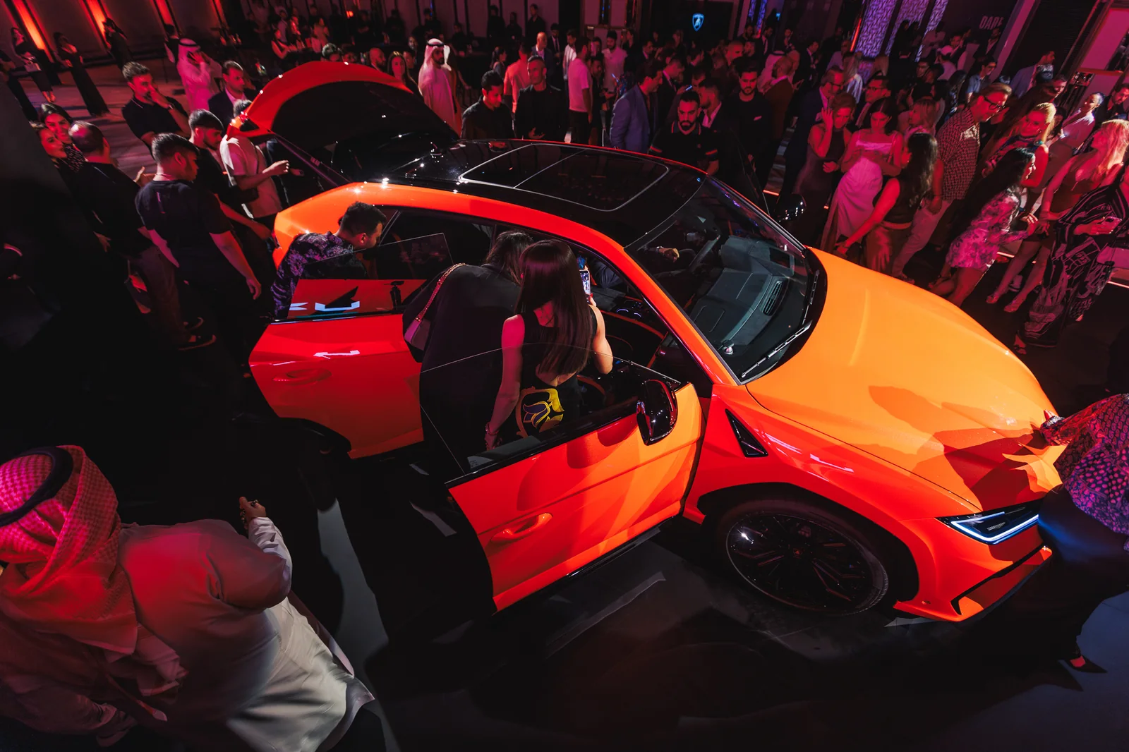 Guests looking over the open doors of the orange Urus SE from above