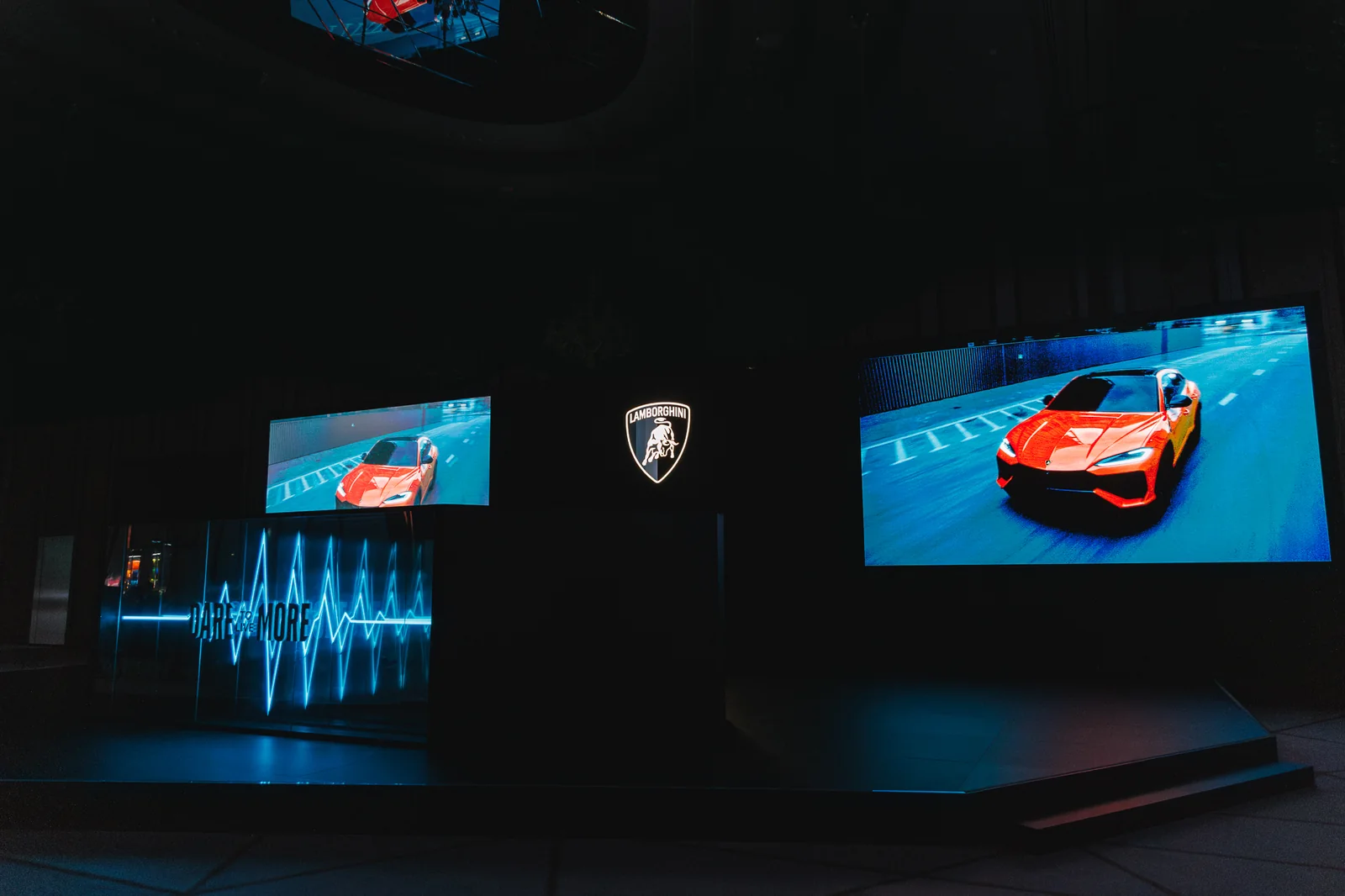 Dark stage with Lamborghini shield and screens showing the Urus SE