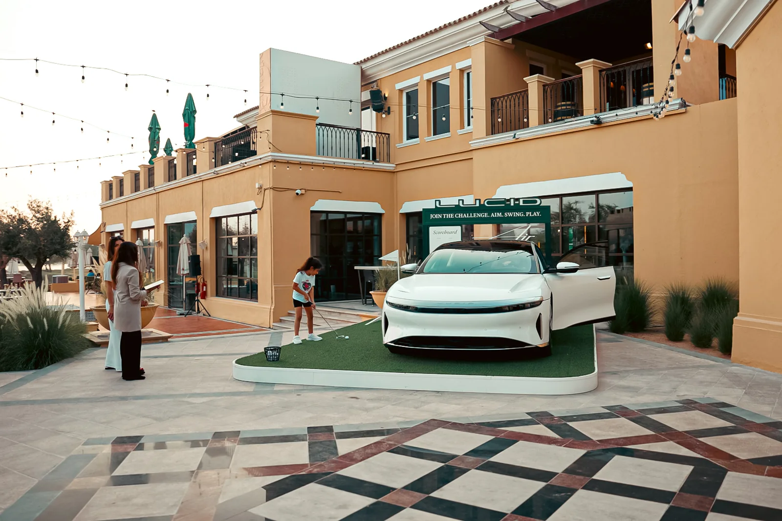 Guests walking around the white Lucid Air on the green at the clubhouse