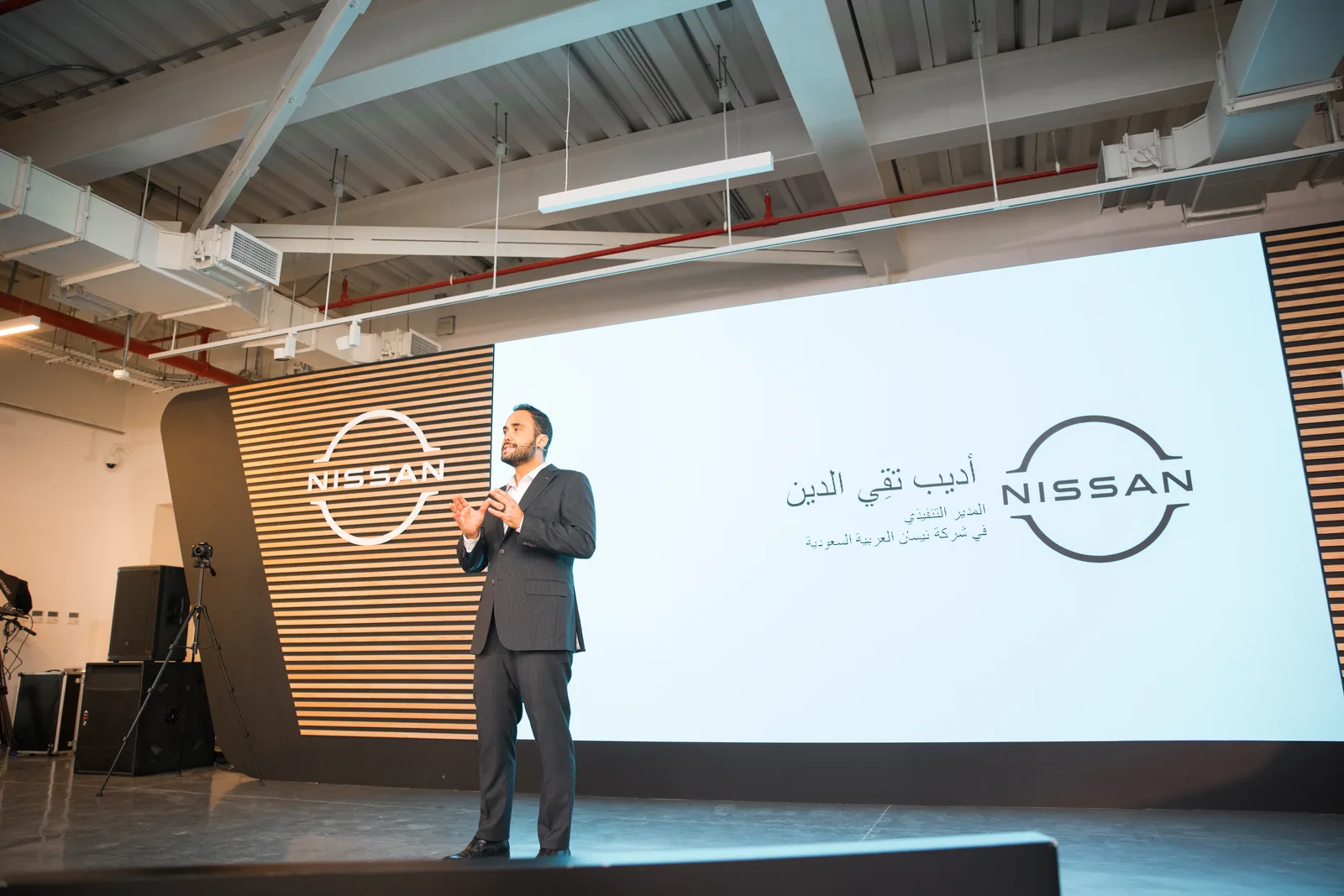 Speaker on stage beside the Nissan logo